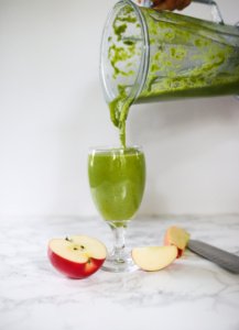 green pineapple apple smoothie in glass. Poured from blender
