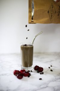 mocha cherry smoothie with coffee beans. Coffee beans being poured into drink.