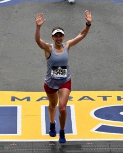 female runner crossing finish line of boston marathon